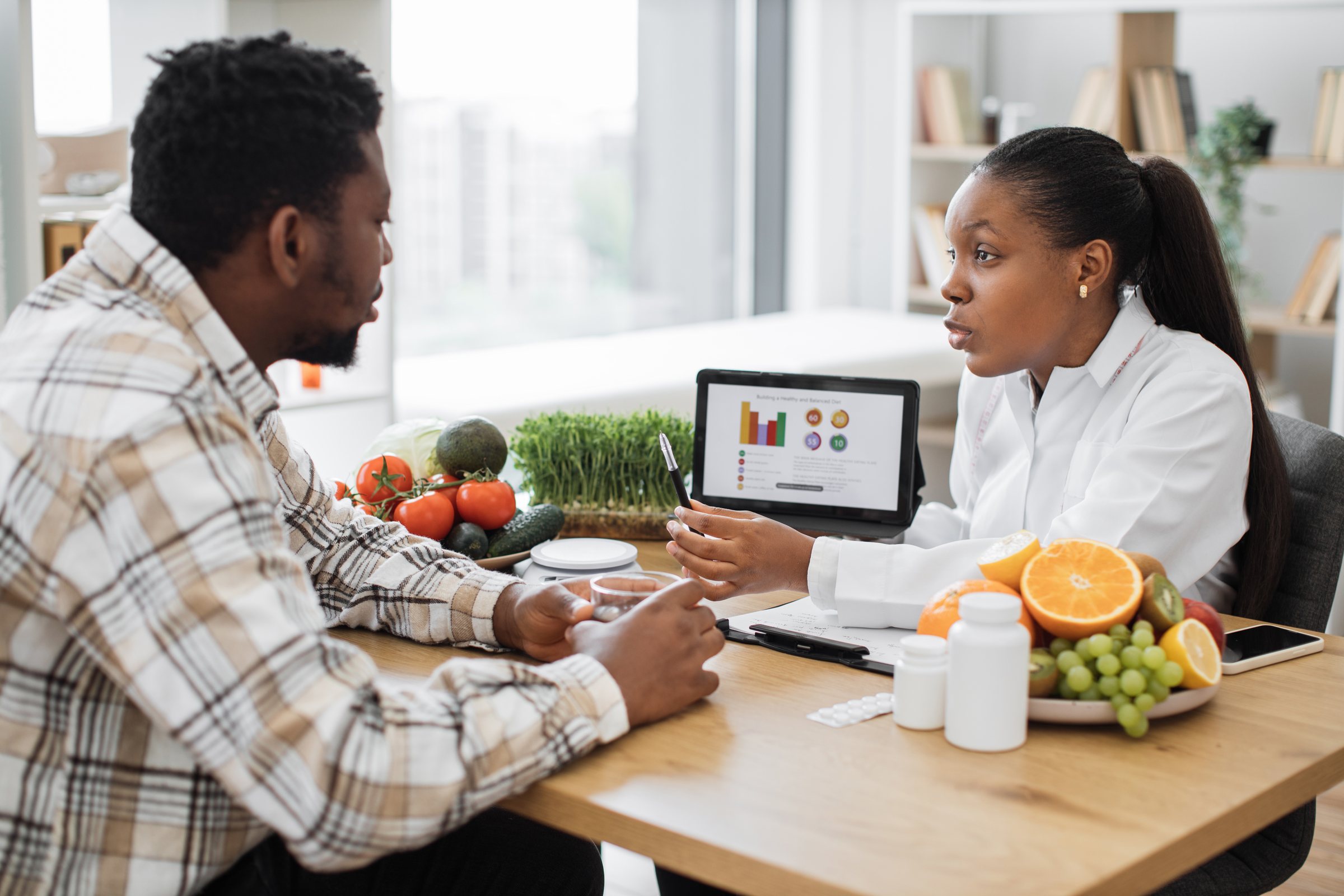 A man discussing a personalised health plan with a female nutritionist